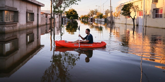 A man rows a dinghy through flood waters in Idiazabal, Argentina, Thursday, March 5, 2015. Flooding throughout four Argentine provinces have forced thousands of people to flee their homes. In the small town of Idiazabal, in the Cordoba province, residents continue to wade through fully submerged streets that have been under water for over one week. While rains stopped on Thursday and are not expected to return over the coming days, floodwaters have not subsided. (AP Photo/Nico Aguilera)