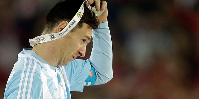 FILE - In this July 4, 2015 file photo, Argentina's Lionel Messi takes off the Copa America silver medal after the final game with Chile at the National Stadium in Santiago, Chile. Messi's shocking decision to stop playing for Argentina could further hurt his already tarnished legacy with his national team. If Messi sticks to his announcement, made in the heat-of-the-moment shortly after Argentina's penalty shootout loss to Chile in Sunday's Copa America final on June 26, 2016, Argentina will be left dwelling on the fact that it was not able to win any significant title while having one of the best players of all time. (AP Photo/Natacha Pisarenko, File)