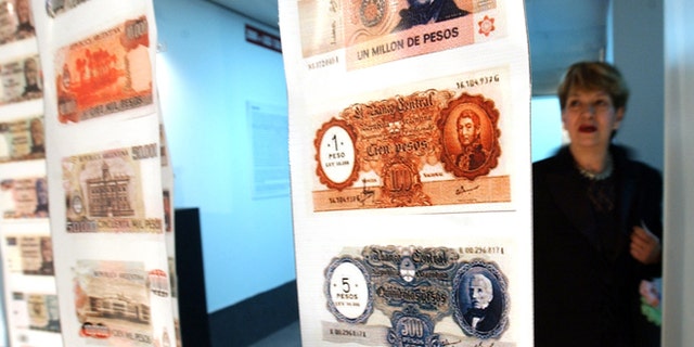 FILE - In this April, 28, 2005, file photo, a woman looks at old currency during the opening of the Foreign Debt Museum in Buenos Aires, Argentina.  The museum, which is the world's first dedicated to a country's debt, opened nearly four years after Argentina staged the largest debt default in modern history. Argentine President Cristina Fernandez said Monday June 16, 2014 that Argentina can't comply with U.S. court orders to pay $1.5 billion to winners of a decade-long legal battle over defaulted debt, the position her country was left in Monday when the U.S. Supreme Court refused to hear her government's final appeal. (AP Photo/Natacha Pisarenko,File)