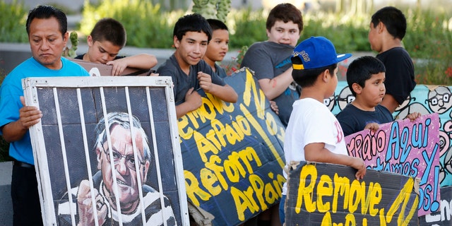 Protesters rally in front of Maricopa County Sheriff's Office Headquarters Wednesday, May 25, 2016, in Phoenix. Arizona taxpayers could be paying out to compensate hundreds of Latinos who were illegally detained when Sheriff Joe Arpaio rounded them up in past immigration patrols. (AP Photo/Ross D. Franklin)