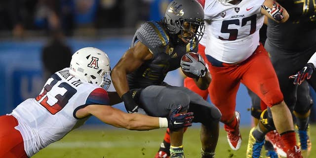 Arizona linebacker Scooby Wright III (33) and linebacker Cody Ippolito (57) close in on UCLA running back Paul Perkins, center, as he rushes during the first half of an NCAA college football game, Saturday, Nov. 1, 2014, in Pasadena, Calif. (AP Photo/Gus Ruelas)