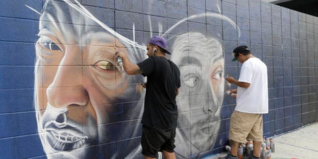 Artists Theo Magma, of Spain, left, and Koka, of Mexico, right, work on a mural, Friday, Dec. 2, 2016, in the Wynwood Art District in Miami, as the annual Art Basel festival continues, featuring poolside parties, blocks of art fairs and outdoor red carpet events. This marks the 15th year that Art Basel has been held in the Miami area. (AP Photo/Alan Diaz)