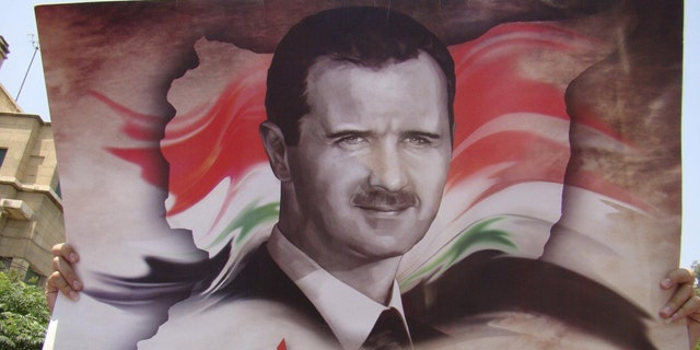 July 11: A government loyalists holds a picture of Syria’s President Bashar al-Assad during a protest outside the U.S. embassy in Damascus.
