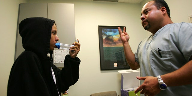 LOS ANGELES, CA - JUNE 06: Asthma program director Alex Aldrete teaches 15-year-old Jesus Ayala the proper use of the new albuterol sulphate inhaler through a holding chamber at the Venice Family Clinic on June 6, 2007 in the Los Angeles, California community of Venice. With a quiet demeanor, Jesus is typical of a large number of teens who become withdrawn and suffer from depression as difficulty breathing isolates them from the physical activities of their peers. Because a federally-mandated ban on chlorofluorocarbons (CFCs) calls for all asthma patients who use albuterol inhalers to switch to an environmentally-friendly inhaler by December 31, 2008, more than 100 community health centers and clinics in California are offering free asthma inhalers to their uninsured and underserved low-income asthma patients through the 2007 ASPIRE Campaign. The ASPIRE Campaign is a partnership between The Childrens Health Fund, National Association of Community Health Centers, National Association of Free Clinics and Direct Relief International. Poor air quality has been blamed for much of the recent rise in childhood asthma cases in the Los Angeles metropolitan area. (Photo by David McNew/Getty Images)