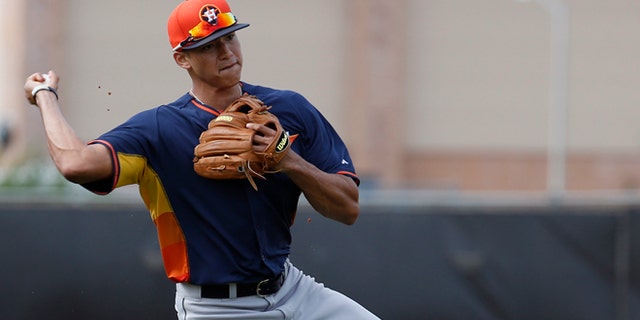 In this Feb. 21, 2014 file photo, Houston Astros' Carlos Correa throws the ball to first base during a spring training baseball workout in Kissimmee, Fla. Correa is one of the top prospects of the Astros, part of a group expected to turn around this once proud franchise and get fans back to the ballpark after three straight 100-loss seasons. (AP Photo/Alex Brandon, File)