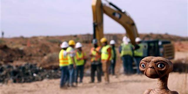 In this April 26, 2014, file photo, an E.T. doll is seen while construction workers prepare to dig into a landfill in Alamogordo, NM.