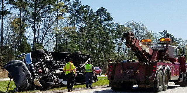 Police officers and emergency workers examine the scene of the accident scene Thursday morning, April 5, 2018, after a tour bus heading to the Masters golf tournament overturned along Interstate 20 near Augusta, Ga. Authorities say at least a dozen people were injured and the bus driver Steven Hoppenbrouwer was charged with DUI. (Joe Hotchkiss/The Augusta Chronicle via AP)