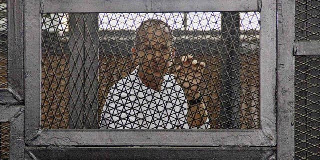FILE - In this May 3, 2014 file photo, Al-Jazeera's award-winning Australian correspondent Peter Greste appears in a defendants' cage in the Police Academy courthouse along with several other defendants during a trial on terror charges in Cairo, Egypt. Australian Prime Minister Tony Abbott said Monday, June 23 that he told Egyptian President Abdel Fatah al-Sisi that the jailed Australian journalist is innocent of charges that he supported the outlawed Muslim Brotherhood. (AP Photo/Hamada Elrasam, File)