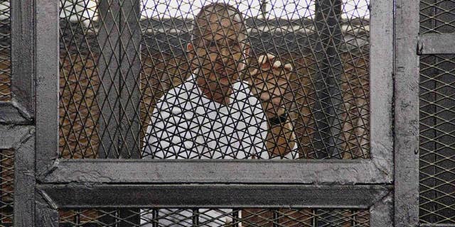 FILE - In this May 3, 2014 file photo, Al-Jazeera's award-winning Australian correspondent Peter Greste appears in a defendants' cage in the Police Academy courthouse along with several other defendants during a trial on terror charges in Cairo, Egypt. Australian Prime Minister Tony Abbott said Monday, June 23 that he told Egyptian President Abdel Fatah al-Sisi that the jailed Australian journalist is innocent of charges that he supported the outlawed Muslim Brotherhood. (AP Photo/Hamada Elrasam, File)