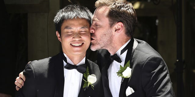 FILE - In this Dec. 7, 2013 file photo, Ivan Hinton, right, gives his partner Chris Teoh a kiss after taking their wedding vows during a ceremony at Old Parliament House in Canberra, Australia. Australia's highest court struck down a landmark law on Thursday, Dec. 12, 2013 that had begun allowing the country's first gay marriages. (AP Photo)