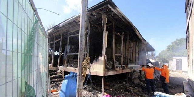 July 21, 2013: In this photo released by the Australian Department of Immigration and Citizenship workers extinguish the last smoldering embers after some 125 asylum seekers rioted at an Australian-run detention center in Nauru. (AP Photo)