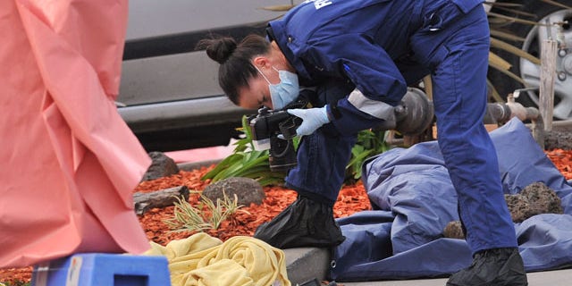 September 24, 2014: A forensic officer documents objects including a blanket at the scene of a fatal shooting at Endeavour Hills Police Station in Melbourne. (AP Photo/AAP Image, Julian Smith)