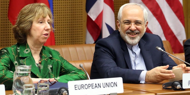 April 8, 2014: European foreign policy chief Catherine Ashton, left, and Iranian Foreign Minister Mohamad Javad Zarif, right, wait for the start of closed-door nuclear talks in Vienna, Austria. (AP Photo/Ronald Zak)