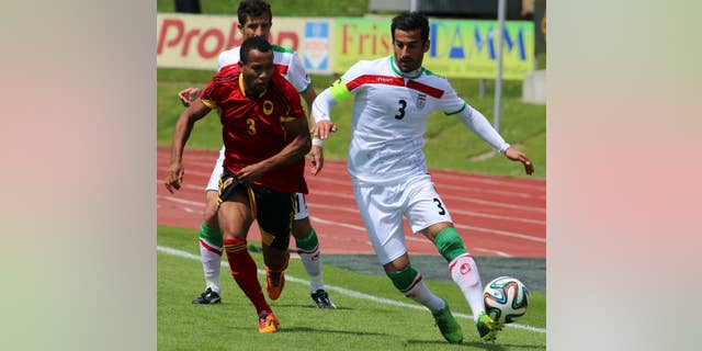 Iran's Ehsan Hajisafi, right, challenges for a ball with Lunguinha, left, of Angola during a friendly soccer match between Iran and Angola, in Hartberg, Austria, Friday, May 30, 2014. (AP Photo/Ronald Zak)