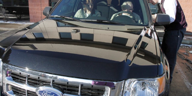 In this Dec. 30, 2010 photo, George and Sheila Snyder, of Washington, Vt., take delivery of their new 2011 Ford Escape from salesman John Cassel, right, at the Formula Ford dealership showroom in Montpelier, Vt. Automakers such as General Motors Co., Ford Motor Co. and Toyota Motor Corp. will report December and year-end sales figures throughout the day, on Tuesday, Jan. 4, 2011. Analysts are forecasting a modest increase that could show that customers bought more vehicles in 2010 than in 2009, when sales plummeted to their lowest levels since 1982. (AP Photo/Toby Talbot)