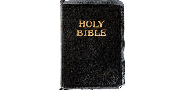 Old Bible isolated on white. Top view, closed, with gold embossed lettering.