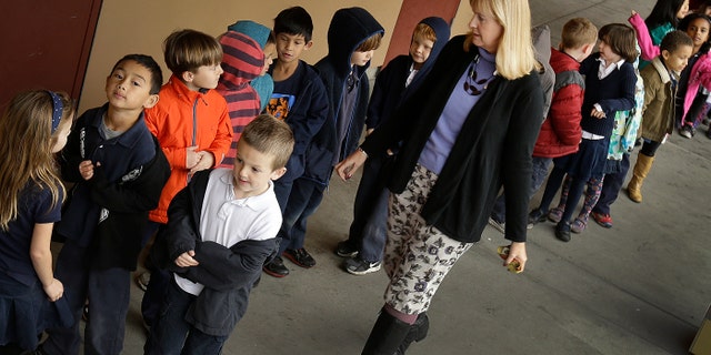 FILE - In this July 24, 2013 file photo, first grade teacher Lynda Jensen walks with her class of 30 children at Willow Glenn Elementary School in San Jose, Calif. Minority and low-income parents are more likely to see serious problems in their schools, from low expectations to bullying and out-of-date technology and textbooks, than those who are affluent or white, according to an Associated Press-NORC Center for Public Affairs Research Poll. The divisions fall along the familiar fault lines of income, education and race that drive so much of American life. (AP Photo/Ben Margot, File)