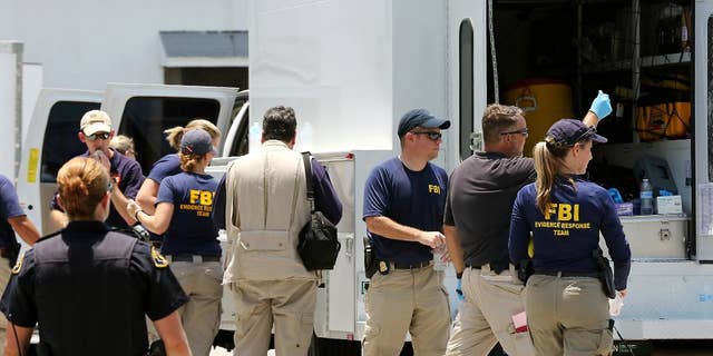 In this photo taken on Monday, July 27, 2015, federal agents and Key West Police gather in a restaurant parking lot in Key West, Fla. A man described by the FBI as an Islamic State sympathizer who hoped to mount attacks on U.S. soil was charged Tuesday with plotting to detonate a nail-filled backpack bomb on a Florida beach. (Rob O'Neal/The Key West Citizen via AP) MIAMI OUT; MANDATORY CREDIT