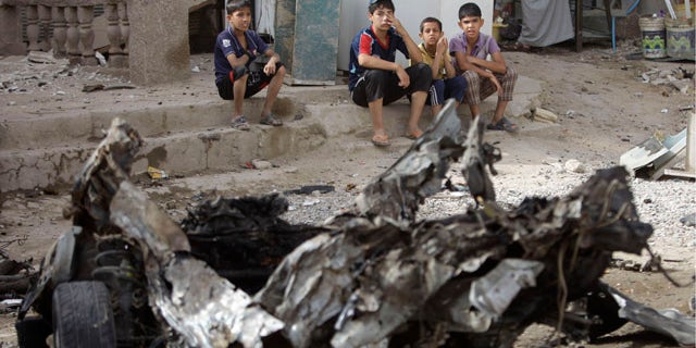 May 22: Boys sit near the scene of a car bomb attack in Baghdad, Iraq. A rapid-fire series of explosions in Baghdad while Iraqis were going to work on Sunday morning killed and wounded scores of people, police said