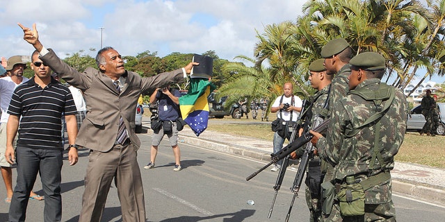 A protester shouts to soldiers during a police strike, in Salvador, Brazil, Monday, Feb. 6, 2012. Murder rates in Brazil's northeastern city of Salvador have more than doubled since the start of a police strike, media reports said Sunday. The strike has thrown a pall over preparations for Carnival in Brazil's third largest city, unleashing a rash of looting and a spike in the murder. (AP Photo/Paulo Macedo)