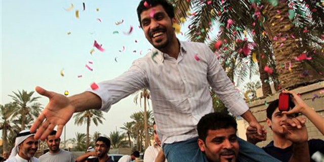 Matar Matar, a former lawmaker with the Shiite opposition Al Wefaq society, reaches out to a well-wisher Sunday, Aug. 7, 2011, as he is carried in front of his home in Daih, Bahrain, on being released from prison pending trial.