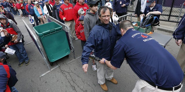 FILE - In this April 20, 2013 file photo, fans pass through security before entering Fenway Park for a baseball game between the Boston Red Sox and the Kansas City Royals in Boston. Major League Baseball has told its 30 teams they must implement security screening for fans by 2015. (AP Photo/Michael Dwyer, File)