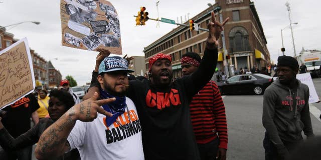A man who calls himself Goldie Loc, left, walks with a man who calls himself Wolfe celebrating on Friday, May 1, 2015, after State's Attorney Marilyn J. Mosby announced criminal charges against all six officers suspended after Freddie Gray suffered a fatal spinal injury while in police custody in Baltimore. Loc said he is a member of the Crips gang and Wolfe said he was with the Bloods gang. (AP Photo/David Goldman)