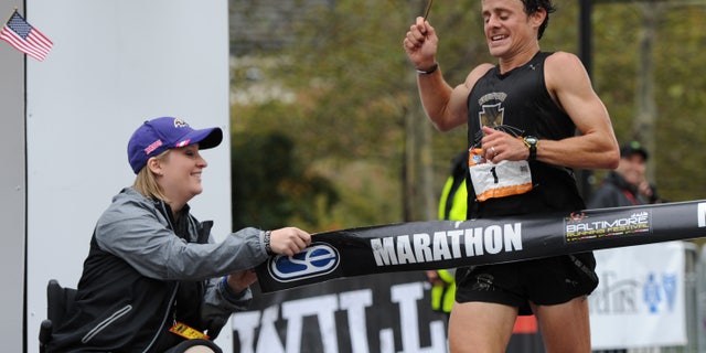 Oct. 12, 2013: Boston marathon bombing survivor Erika Brannock holds an end of the tape at the finish line as runner David Berden wins the Baltimore marathon.