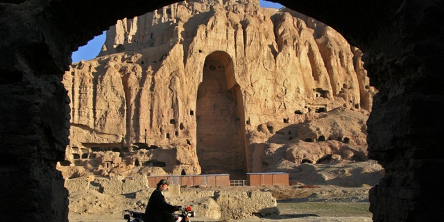 An Afghan man rides his motorcycle past the remains of the Giant Buddha destroyed by the Taliban in March 2001 in central Bamiyan province 162 miles northwest of Kabul March 30, 2005.