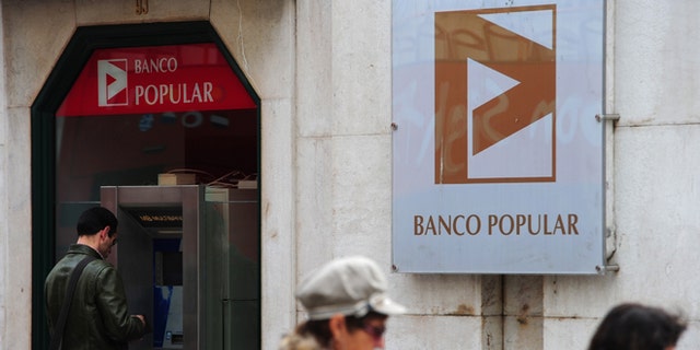 LISBON, PORTUGAL - MARCH 29: A man stands behind a cash machine of the Banco Popular on March 29, 2011 in Lisbon, Portugal. The pressure continues on Portugal's weak economy to accept a bailout - estimated to be as high as 80 Million Euros - after last week's resignation of Prime Minister Jose Socrates. (Photo by Jasper Juinen/Getty Images)