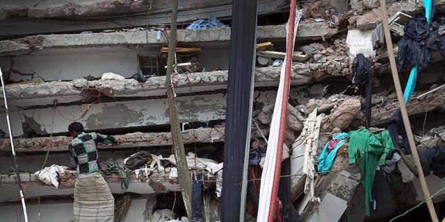 In this April 30, 2013 file photo, a worker toils in a collapsed garment factory building in Savar, near Dhaka, Bangladesh.