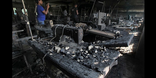 Nov. 26, 2012: A man takes photographs inside a garment-factory where a fire killed more than 110 people Saturday on the outskirts of Dhaka, Bangladesh.
