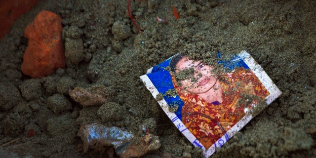 May 5: A photo of a missing garment worker is partially buried in soil at the site of the garment factory building collapse in Savar, near Dhaka, Bangladesh.