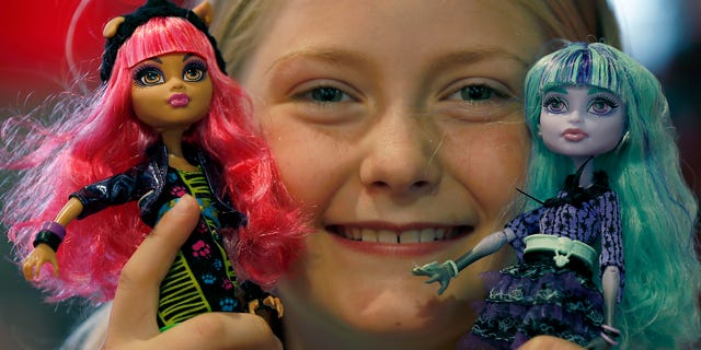 In this Thursday, June 27, 2013, photo,Tegan, 9, poses with Monster High Dolls as part of a Christmas toy preview at the toy store Hamleys in London. Mattels Monster High Dolls, with neon hair and punk clothing, have grown to an estimated $500 million in annual sales since debuting in 2010. (AP Photo/Frank Augstein)