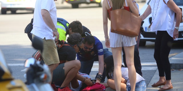 An injured person is treated in Barcelona, Spain, Thursday, Aug. 17, 2017 after a white van jumped the sidewalk in the historic Las Ramblas district, crashing into a summer crowd of residents and tourists and injuring several people, police said.