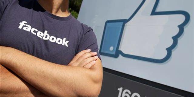 A Facebook worker waits for friends to arrive outside of Facebook headquarters in Menlo Park, Calif.