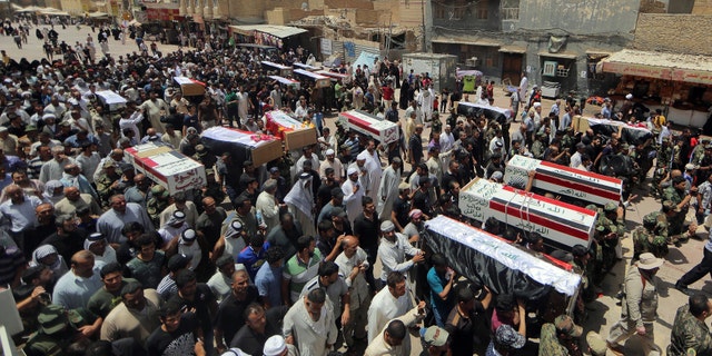 Mourners carry the flag-draped coffins of 15 militia members of a Shiite group, Asaib Ahl al-Haq, or League of the Righteous, who were killed in Beiji, Iraq, from fighting with Islamic State militants, according to their families, during the funeral procession in Najaf, 100 miles (160 kilometers) south of Baghdad, Monday, June 8, 2015. (AP Photo/Jaber al-Helo)