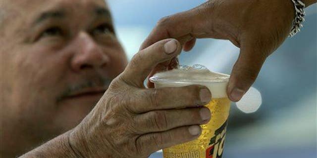 A man buys beer in an outdoor bar at Caracas's auto show, Sunday, Oct 7, 2007. Venezuela's President Hugo Chavez is on a moral crusade, preaching against vices from alcohol to cholesterol, vowing to curb whisky imports and ordering beer trucks off the street.