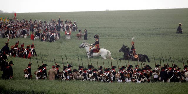 FILE - In this June 20, 2010 file photo troops march through a field during a re-enactment of the 1815 Battle of Waterloo in Waterloo, Belgium. Belgium is looking to change a commemorative Waterloo coin to an unofficial value of 3 euros ($3.18) to avoid what it called opposition from France. Coining unofficial values do not need backing from other countries in the 19-nation eurozone. Battle of Waterloo commemorations begin June 18, 2015. (AP Photo/Virginia May, File)