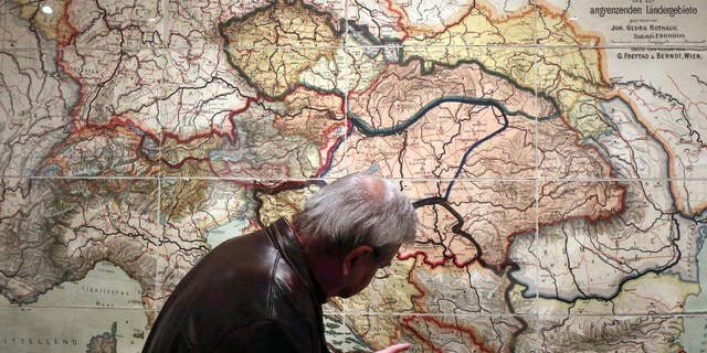 ADVANCE FOR SUNDAY JUNE 15 2014 TO GO WITH STORY WWI-THE GREAT WAR -In this Tuesday, April 1, 2014 photo, a visitor looks at a school wall map of the Austrian-Hungarian Empire from 1900 that was corrected with new borders after World War I at a special exhibition on World War I at the Schallaburg castle, in Austria. (AP Photo/Ronald Zak)