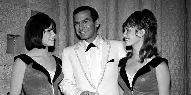 In this 1965 file photo, actor Ben Gazzara poses with dancers Sandy Garrett, left, and Victoria Scruton while filming an episode of the TV series "Run for Your Life," in Los Angeles.