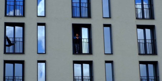 A man stands on a balcony of a hotel, as a pigeon, flies by, in central Gothenburg, Sweden, Thursday, Aug. 14, 2014. (AP Photo/Petros Karadjias)