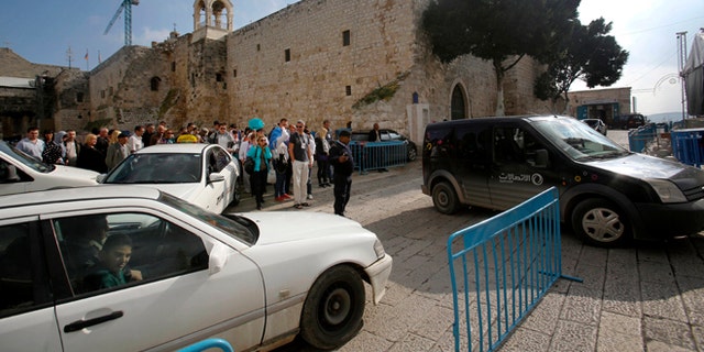 Dec. 14, 2014: Tourists walk and cars drive past the Church of the Nativity in Bethlehem, West Bank. Its Christmas season and the little town of Bethlehem is jammed with a big-city problem: Traffic snarling streets everywhere, including around the church marking the spot where tradition says Jesus was born.