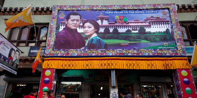 A large banner of King Jigme Khesar Namgyal Wangchuck and future Queen Jetsun Pema is seen on a storefront in the capital of Thimphu, Bhutan, Wednesday, Oct. 12, 2011. The 31<strong>–</strong>year-old reformist monarch of the small Himalayan Kingdom will wed his commoner bride in a series ceremonies set for Thursday.”/</source></source></picture></div>
<div class=