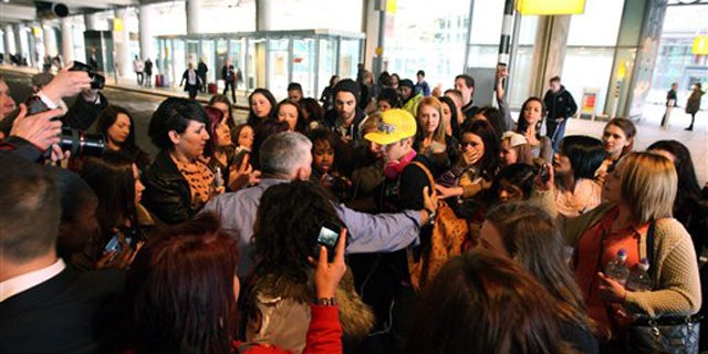 April 23, 2012: Canadian singer Justin Bieber wearing a yellow hat is greeted by fans as he arrives ahead of his album launch at Heathrow Airport, London.