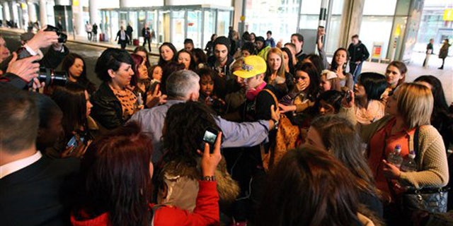 April 23, 2012: Canadian singer Justin Bieber wearing a yellow hat is greeted by fans as he arrives ahead of his album launch at Heathrow Airport, London.