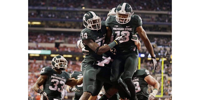 December 7, 2013: Michigan State's Tony Lippett (14) celebrates with Bennie Fowler (13) after a 33-yard touchdown reception by Lippett during the first half of the Big Ten championship game in Indianapolis. (AP Photo/Michael Conroy)