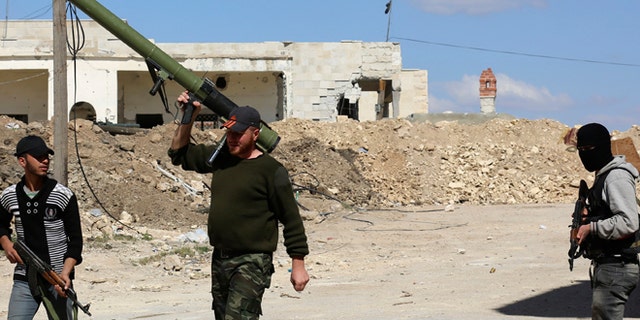 April 9, 2014: Rebel fighters carry their weapons as they walk along a street in the town of Morek in Hama province.