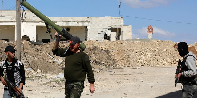 April 9, 2014: Rebel fighters carry their weapons as they walk along a street in the town of Morek in Hama province.