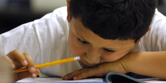 A young student in a second grade bilingual class looks closely at a math exam. (Photo by Tim Boyle/Getty Images)